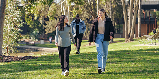 Two deakin students walking and smiling together on campus.