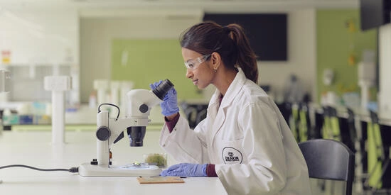 A Deakin science student in a lab wearing a white coat and goggles,