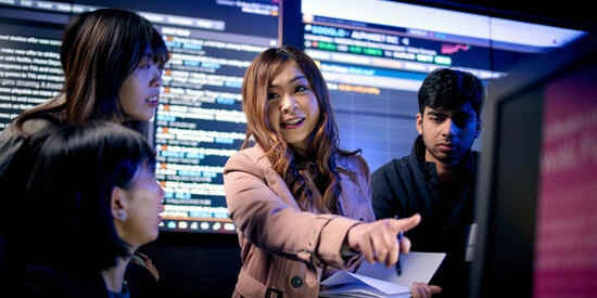 Four Deakin commerce students engaging with stock market feeds in the DBS trading room.