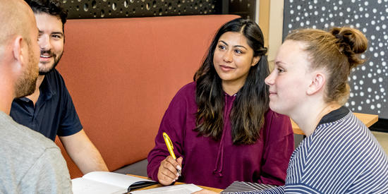 Two education and teaching students sit at a table on campus studying.