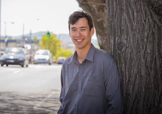 Alex Suwitra, an international studies student at Deakin, leaning against a tree.