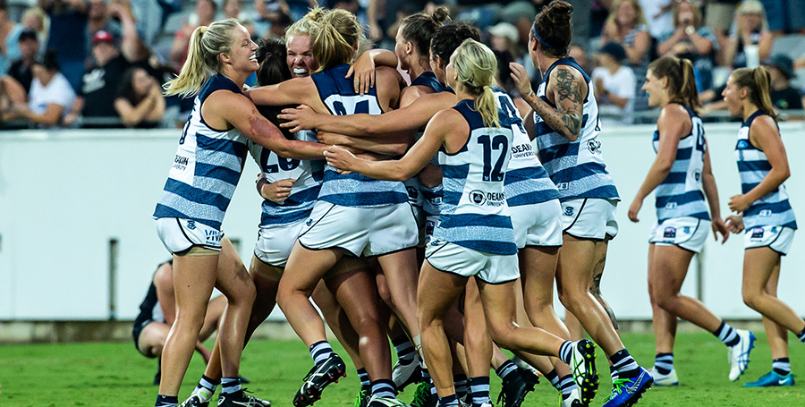 Action shot of AFLW Geelong team players playing football on the field together.