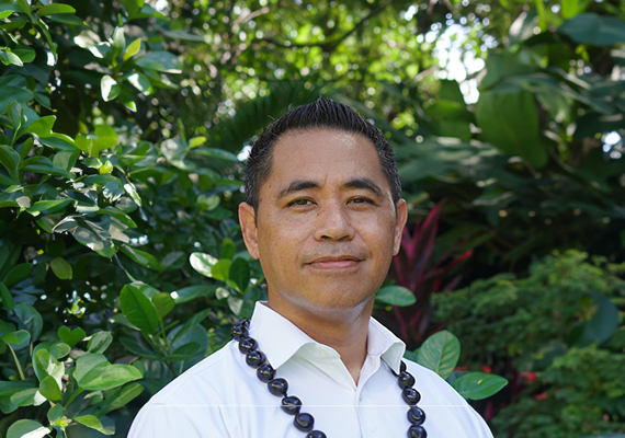 Sam Saili standing in front of some trees