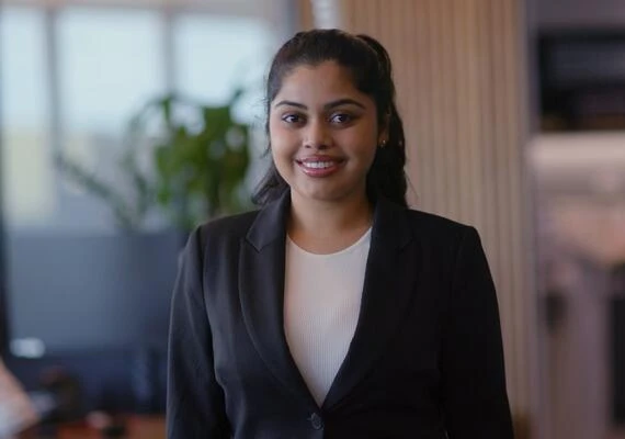 Deakin Law graduate Swathika, wearing business attire and smiling at the camera.