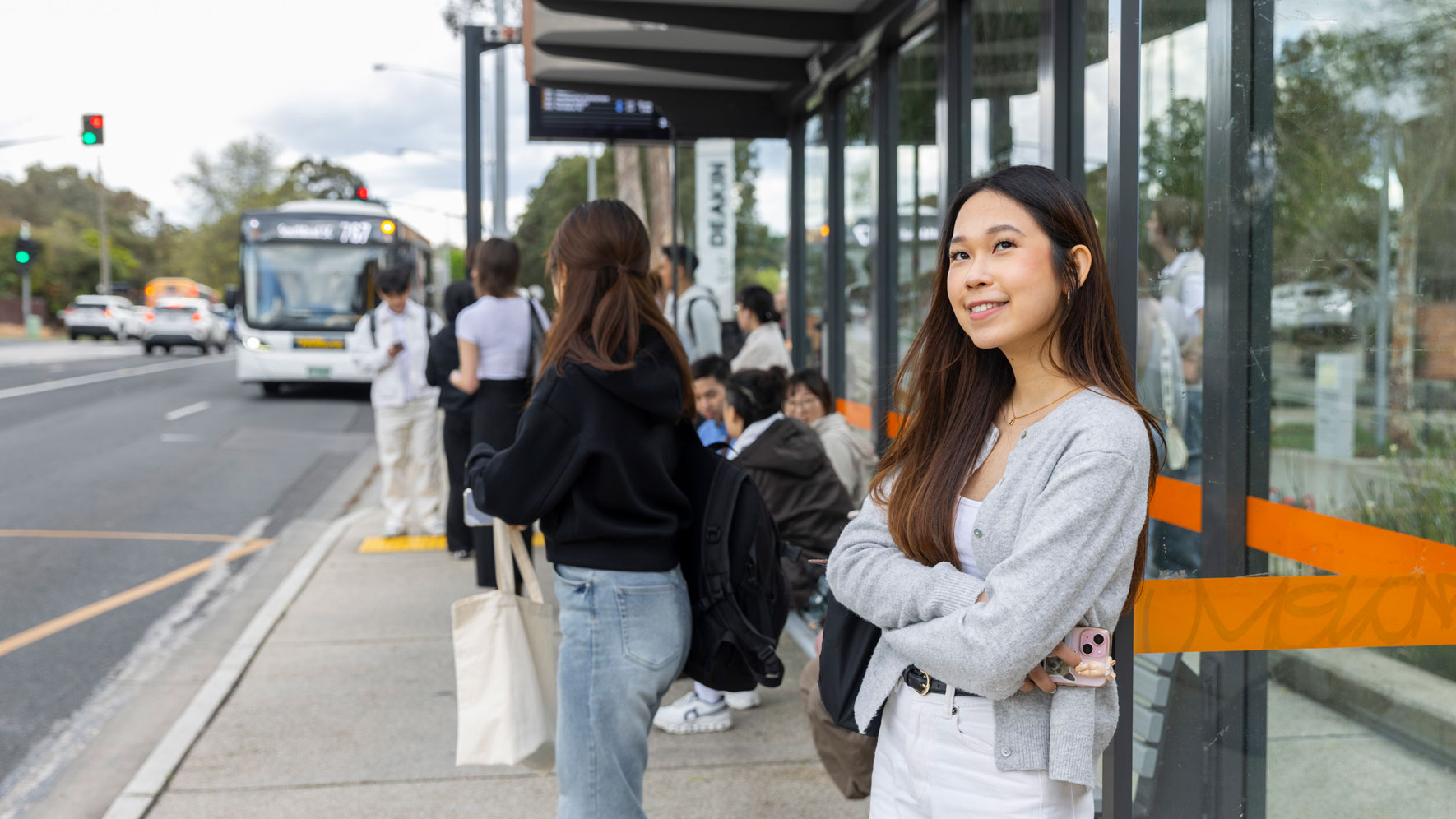 Image of a female student waiting at a bus stop
