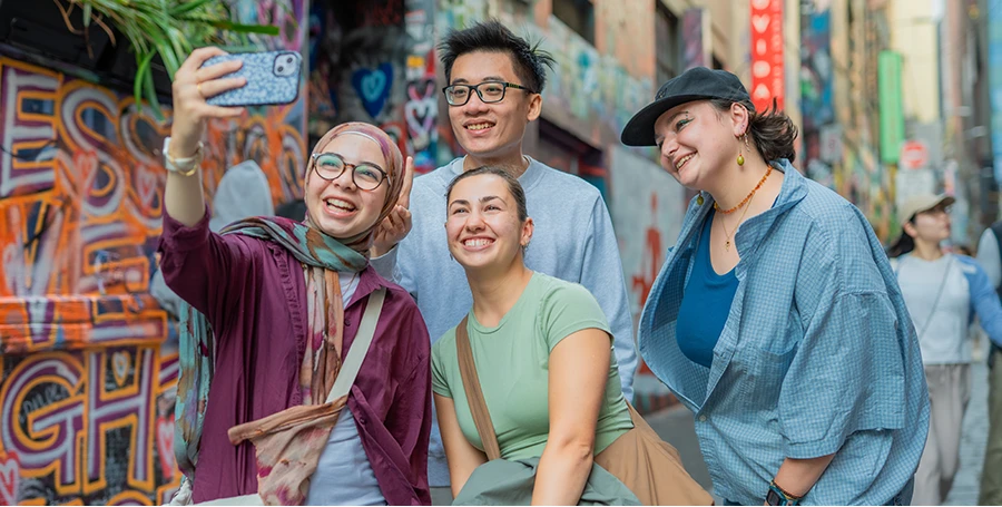 International Summer School students taking a selfie in one of Melbourne's colourful laneways.