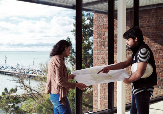 Two Deakin construction management students looking at a building blueprint