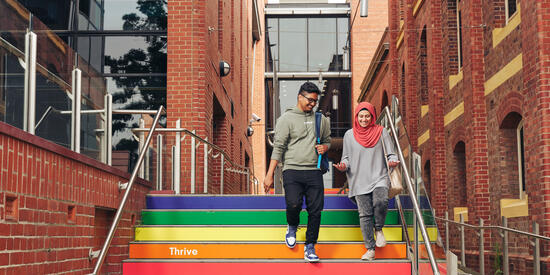 Two students walk down rainbow staircase at the Geelong Waterfront Campus.
