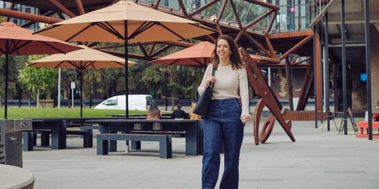 A Deakin student walks at the Melbourne Burwood Campus with seating in the background. 