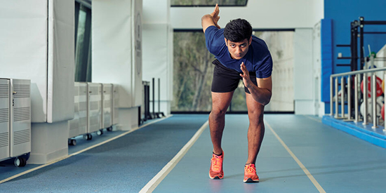 A student gets ready to sprint on a running track. 