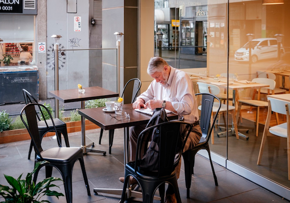A person reading newspaper in cafe.