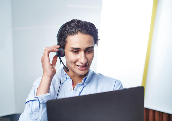 A Deakin staff member on a call on a laptop wearing a headset.