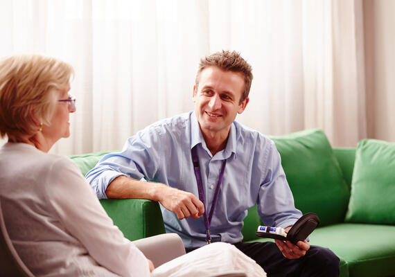 A medical professional talks on a couch with a client.