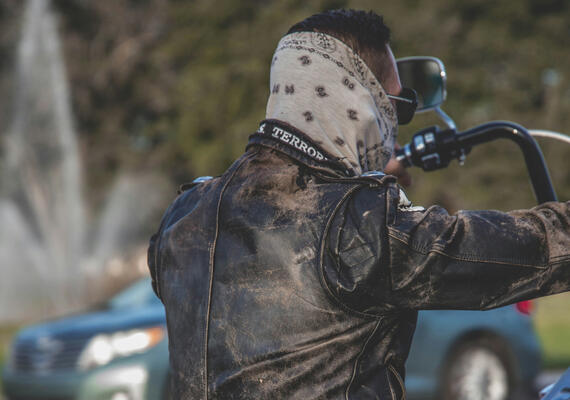 A person riding a motorcycle wearing a bandana.
