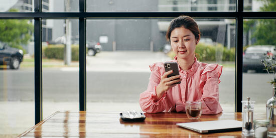 Student looking at her phone at a table in a cafe