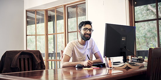 A person sits at their computer at home and studies.