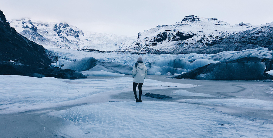 Scenic picture of deakin student georgia kate hourticolon standing in field of snow and mountains in Iceland.