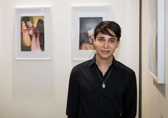 Photo of student Alex Syrian in the gallery with his art works.