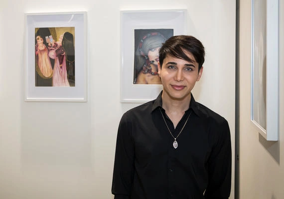 Photo of student Alex Syrian in the gallery with his art works.