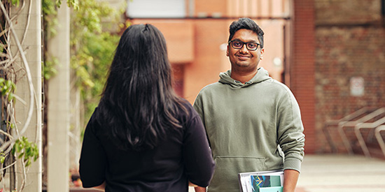 Deakin TAFE student smiles to camera while chatting to another Deakin student.