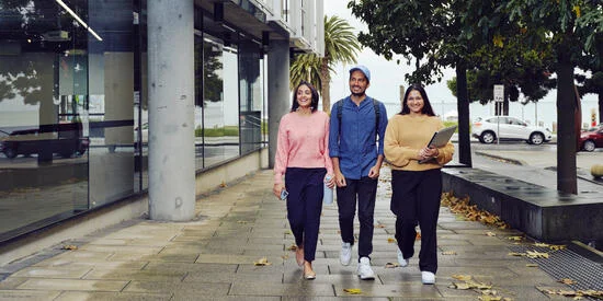 Three students walking around the outside of the Geelong Waterfront Campus.