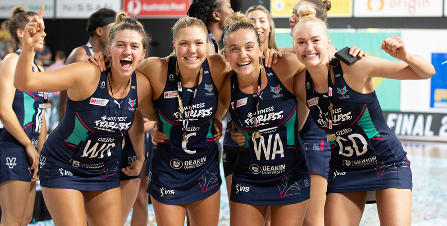 Team photo of the Melbourne Vixens netball team smiling and celebrating together.