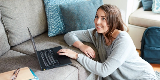 Student working on laptop on sofa