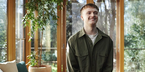 A Deakin online student standing in front of a window
