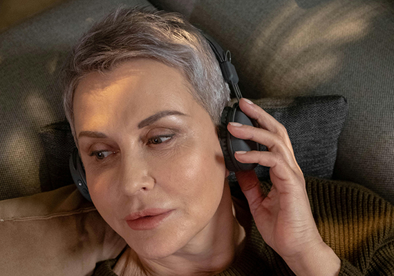 A close-up shot of an older person's face listening to headphones