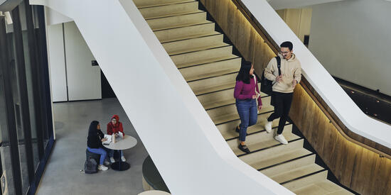 Two Deakin students walking down a staircase on campus.