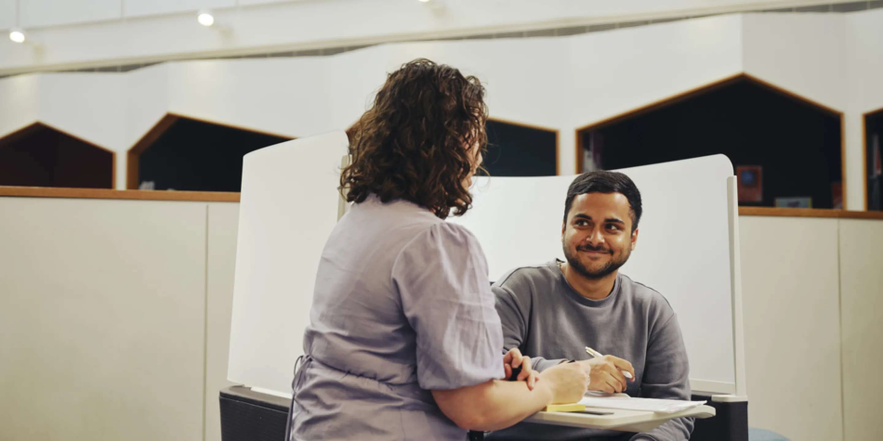 A staff member sits talking with a smiling student