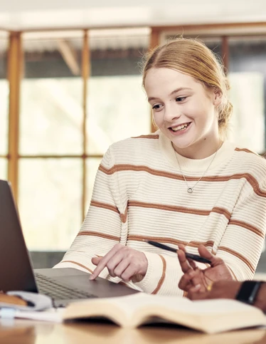 Two students studying together around a dining room table.