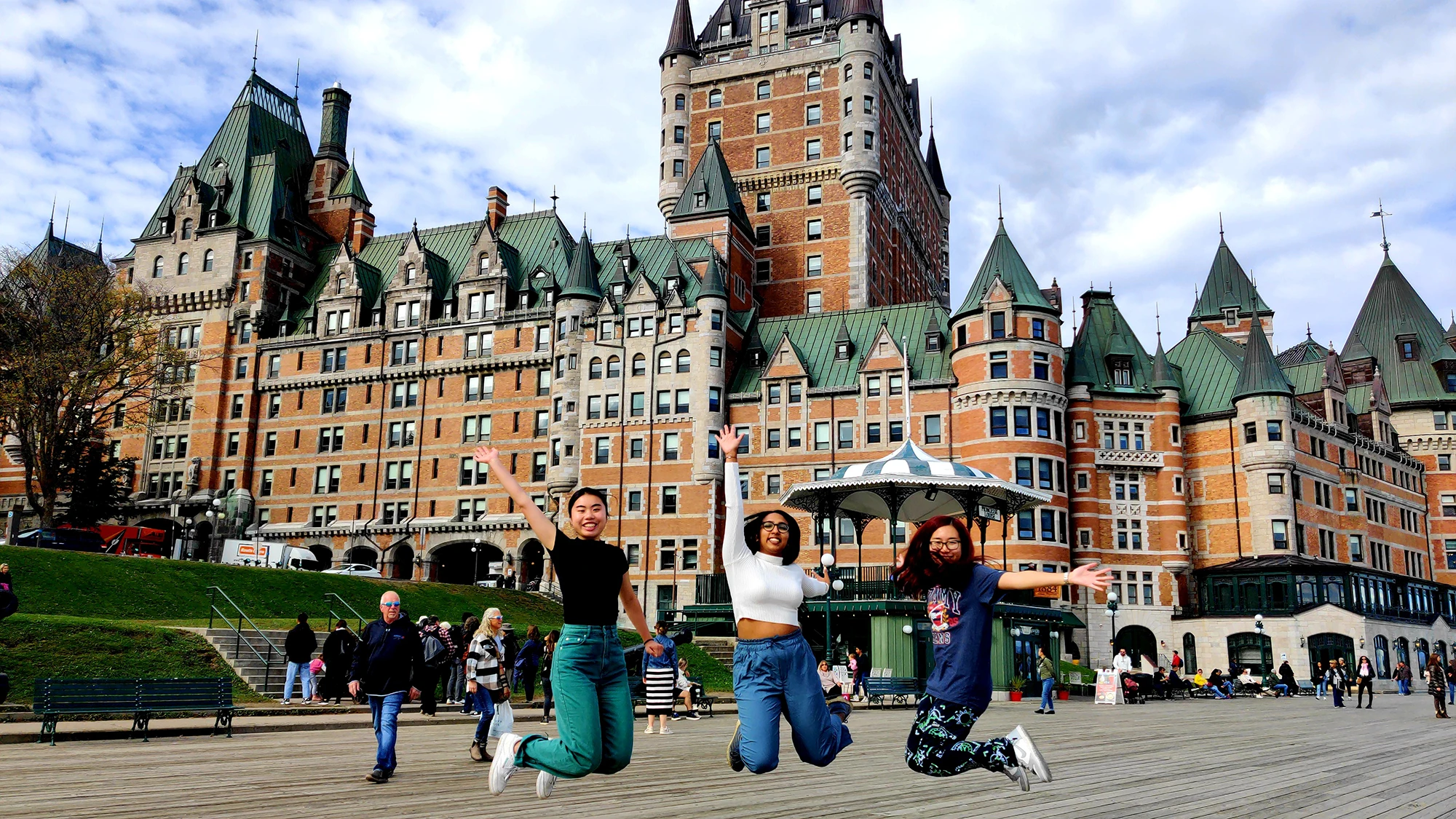 Kaviya and two other girls jumping in the air to pose for a photo, with a grand building in the background