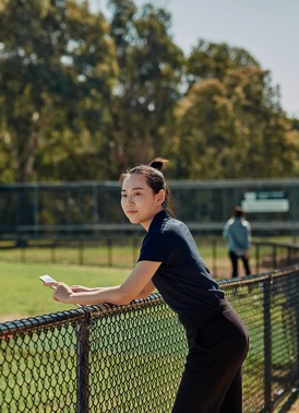 Sport student leaning on fence