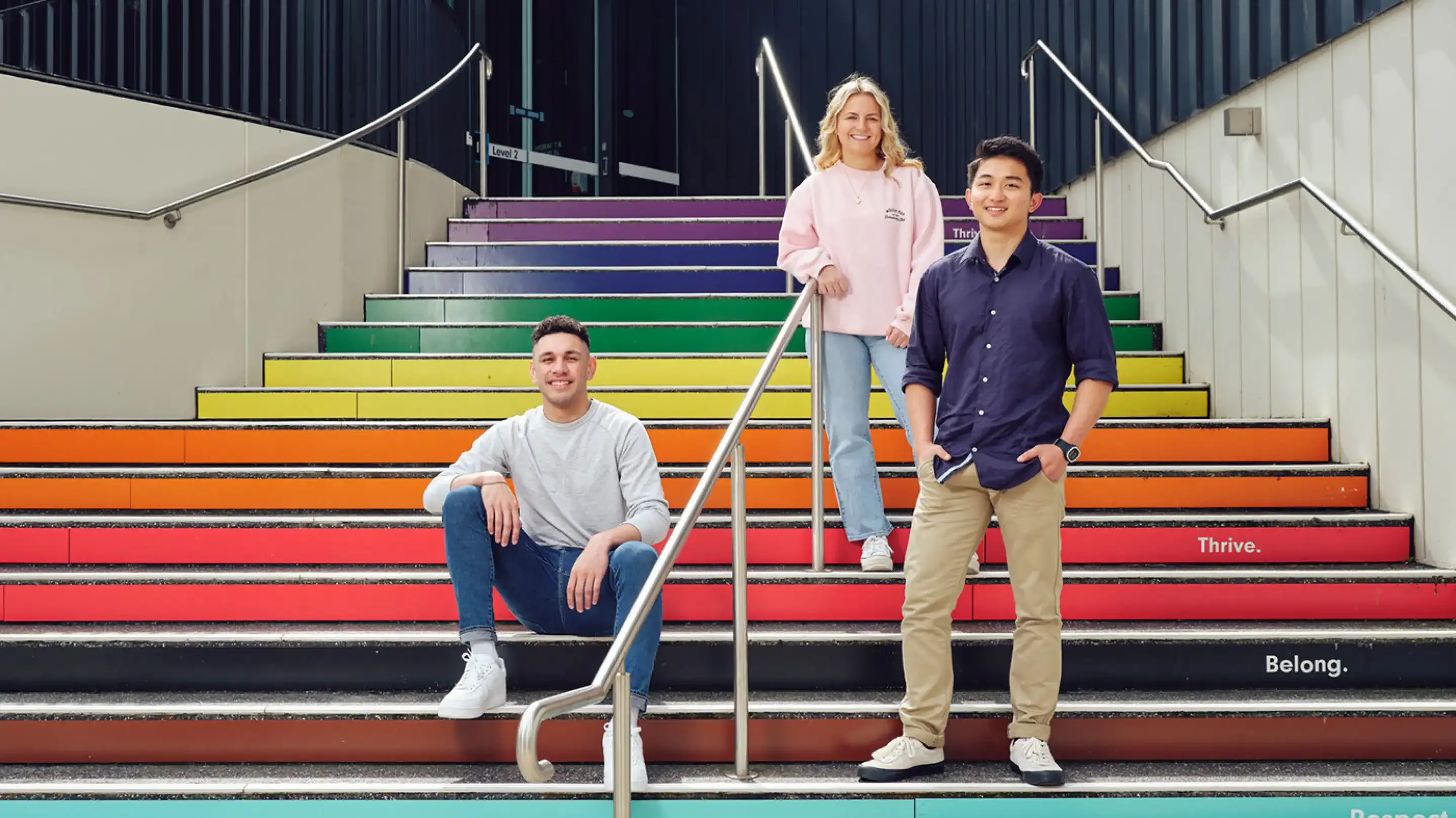 Three students on rainbow steps at Deakin Geelong Campus