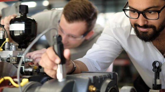Two Deakin master of engineering professional students work on motors in a lab.