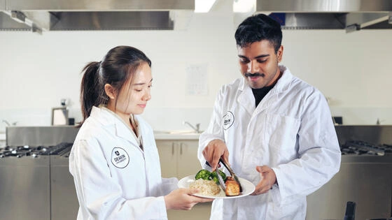 Deakin master of nutrition and population health students in a campus lab studying a plate of food.