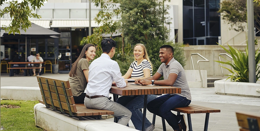 Four Deakin students sit at a table at the Deakin Burwood Campus cafe. 