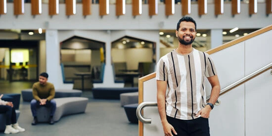 Smiling student standing at bottom of staircase