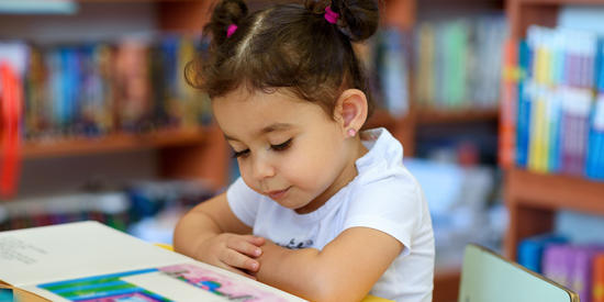 Child reading a book in the library.