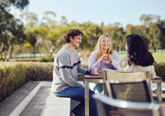 Three students sitting outside and socialising on Geelong Waurn Ponds Campus.