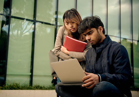Two business students looking at a laptop.