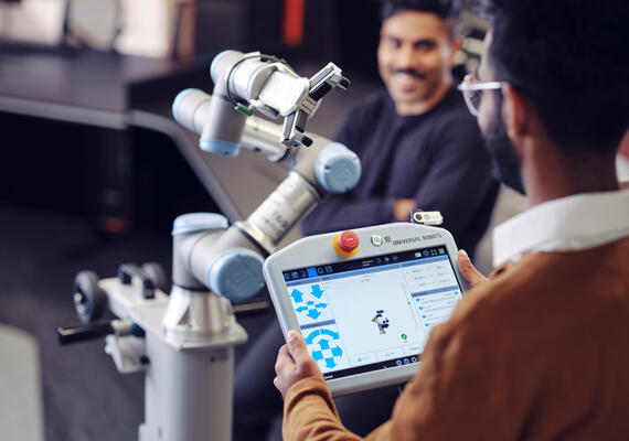 Student uses a tablet computer to control a sophisticated articulated robotic arm fitted with sensors