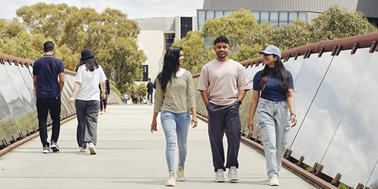 Three Deakin students walk across a bridge on the Melbourne Burwood Campus. 