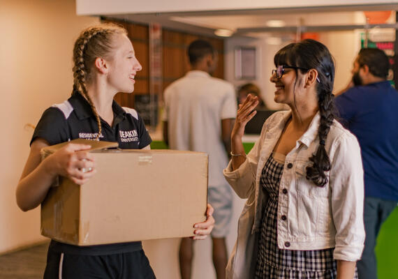 Deakin students moving into campus accommodation holding a box.