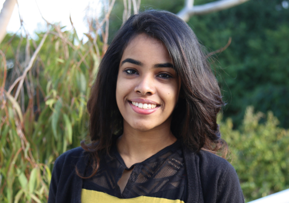 Deakin student Onali standing outside in front of trees smiling at camera.