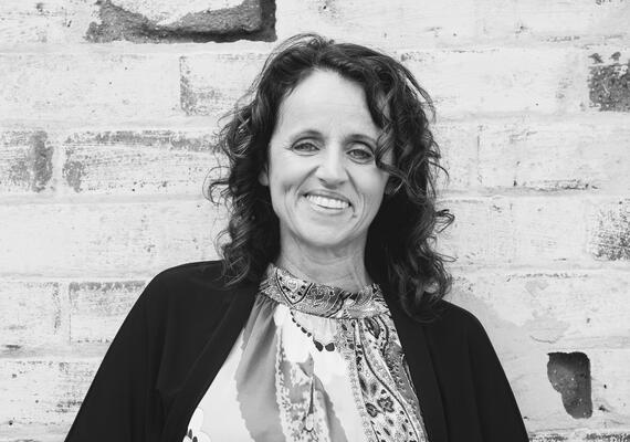 Deakin Master of International and Community Development graduate profile image of Kelley Chisholm standing in front of a wall at Deakin's Melbourne Burwood Campus.
