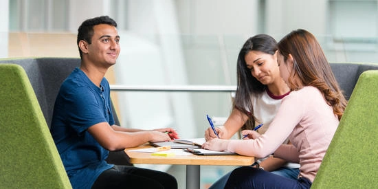 Three Deakin students working together at a table near a window