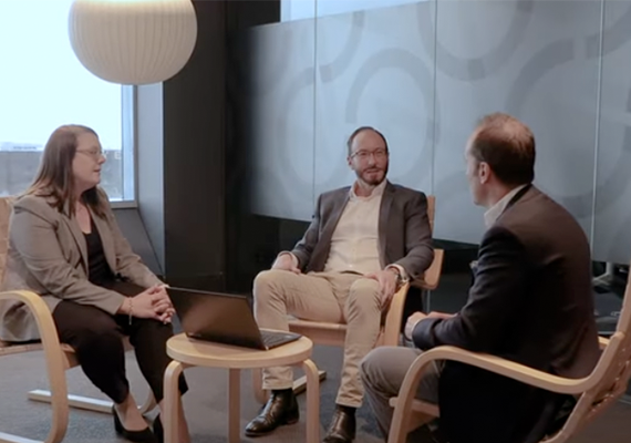 Three people sitting in a corporate office talking.