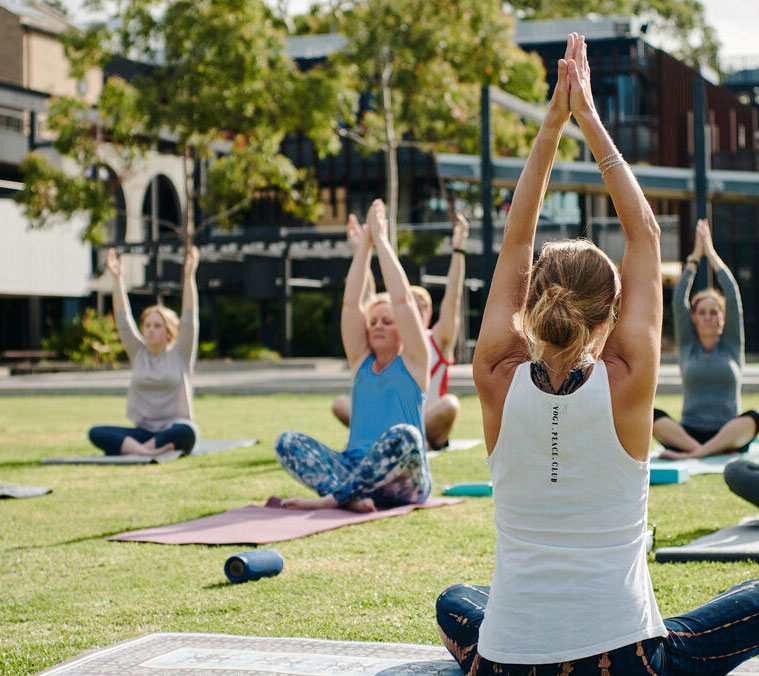 Students doing yoga outside on grass on a Deakin uni campus